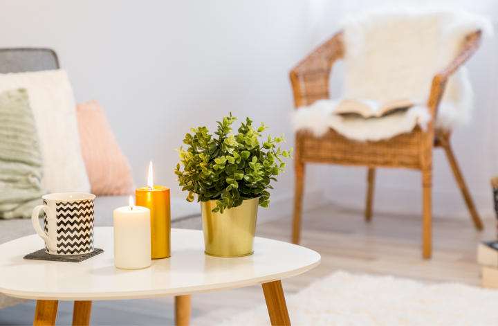 white coffee table decorated with mug candles and plant pot